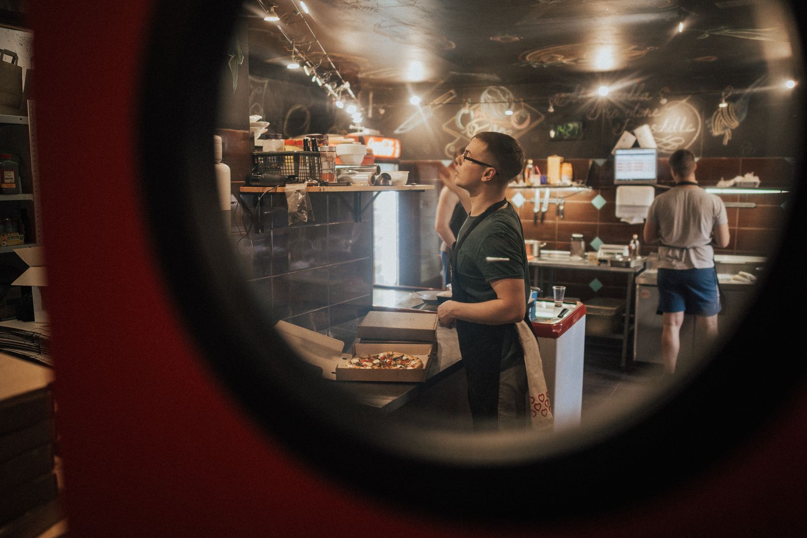 A packed pizza shop dining room with staff running orders