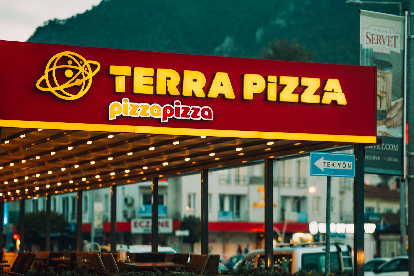 Multi-location pizza chain shop front with a lit sign
