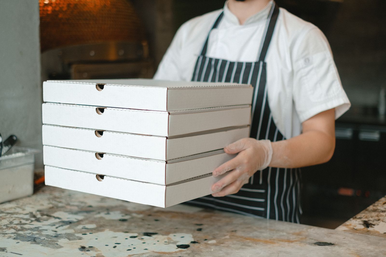 Single-shop pizzeria owner behind the counter, tallying the day's tickets